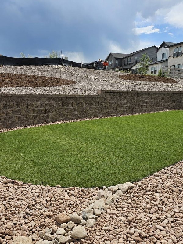 Block retaining wall with artificial turf and river rock drainage in Colorado Springs