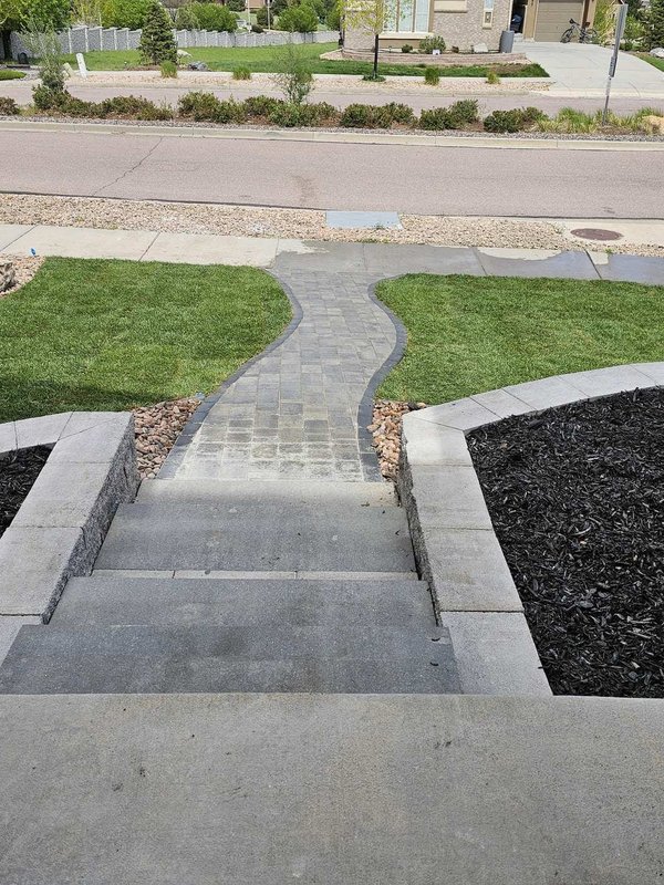 Paver walkway with steps, stone pillars, and fresh sod at a Colorado Springs home